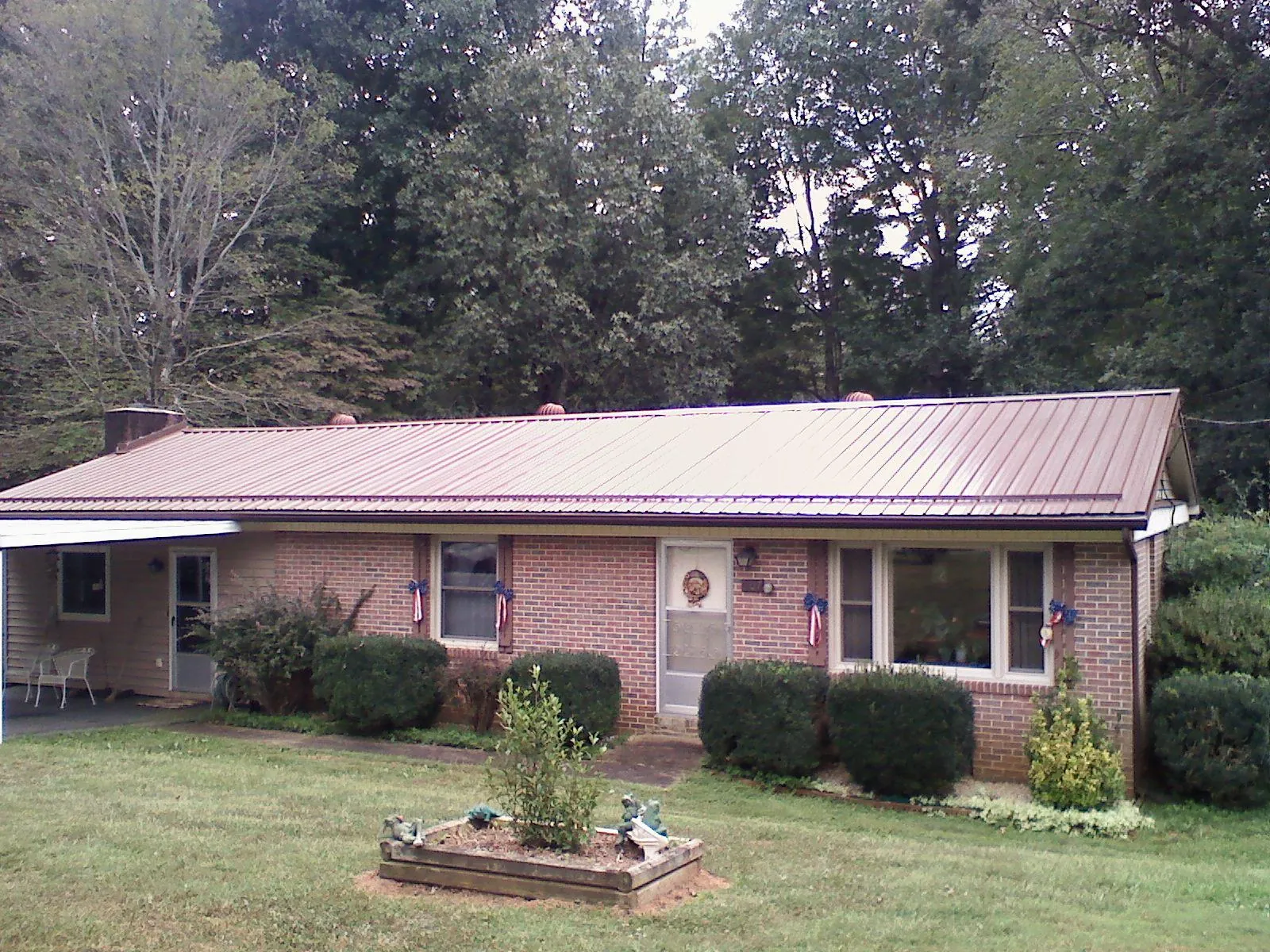Bronze metal roof on a brick ranch home with a carport in Milton
